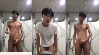 Skinny Asian boy in white mask and hoodie strips in public bathroom